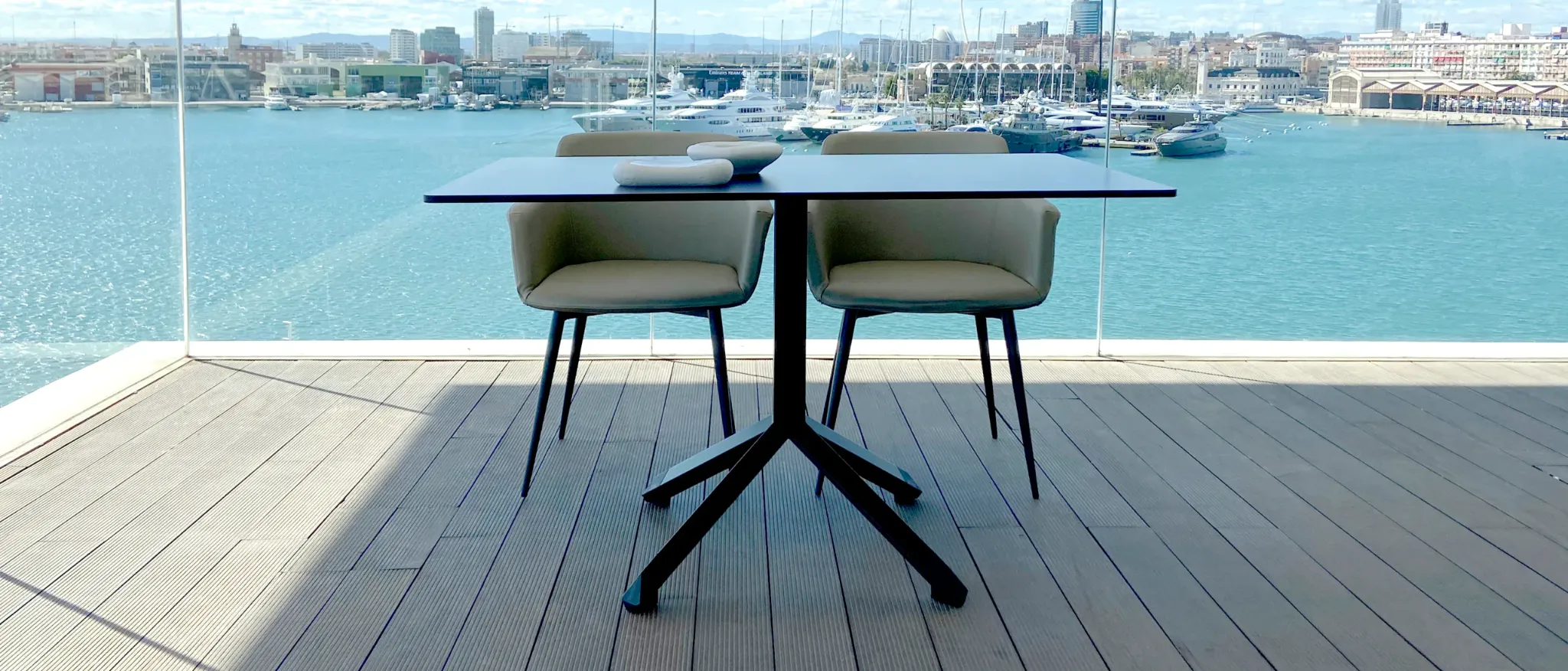 Mesa de esTABLEes con base piramidal en una terraza con vistas al puerto