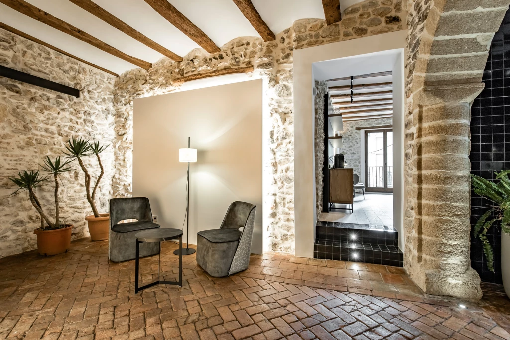 Zona de estar de ABBI Suites con piedra vista, vigas de madera y asientos de Casual