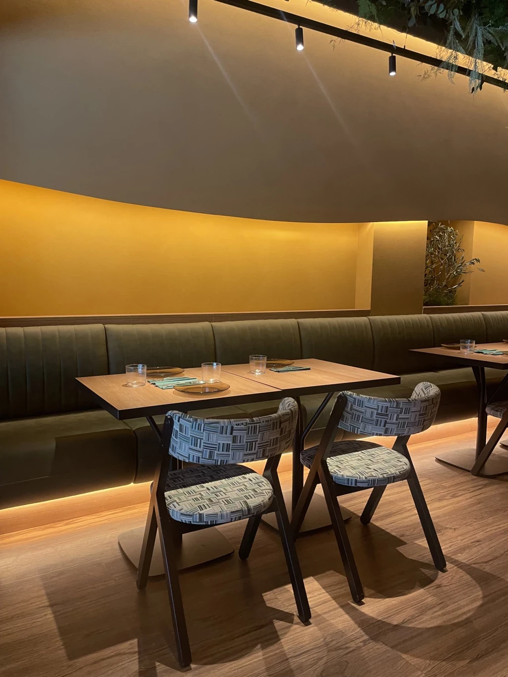 Mesa de comedor y sillas tapizadas junto a una bancada en el restaurante Raro