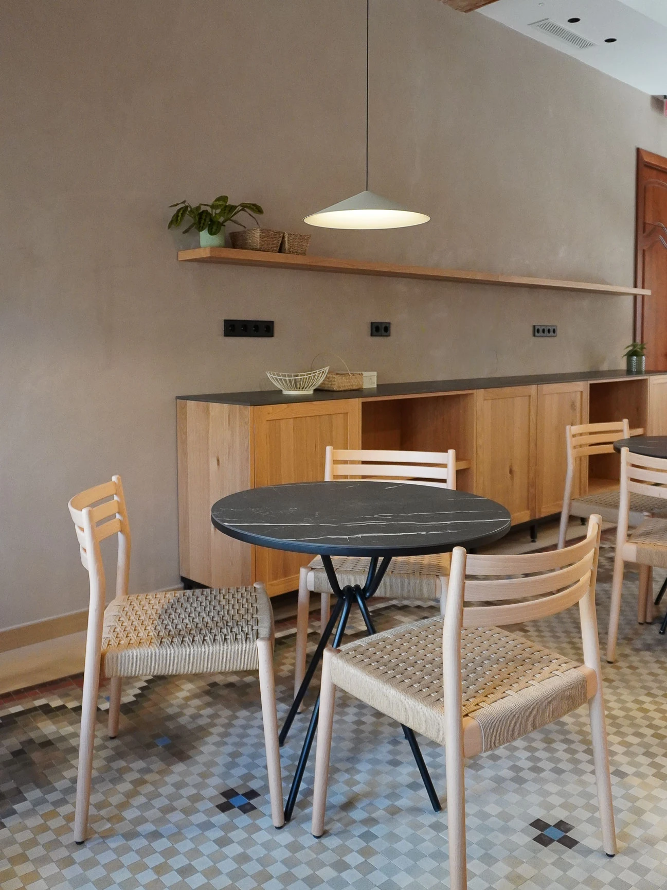 Mesa redonda y sillas de madera en una zona común de Tradere