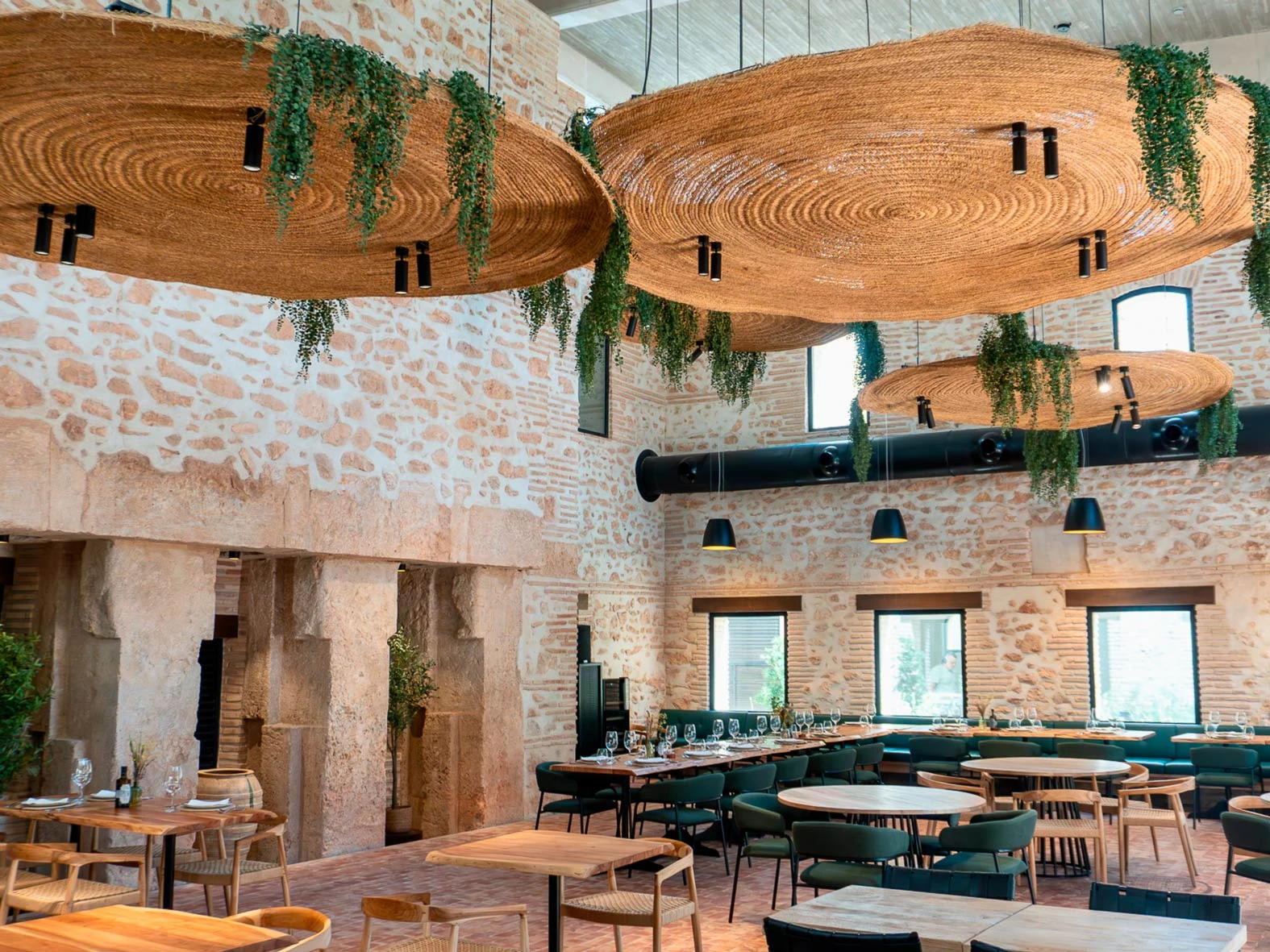 Zona de comedor del complejo Tradere con mesas y asientos en un ambiente de piedra y madera